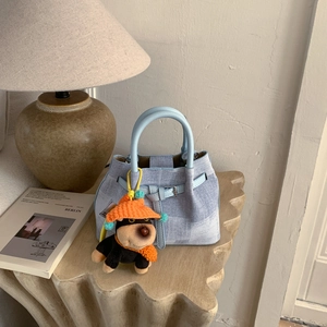 Hellblaue Handtasche in Denim-Optik mit süßem Hunde-Plüschanhänger auf Steinsockel