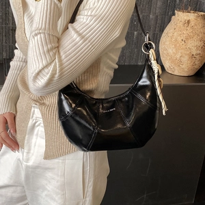 Detail of black glossy hobo bag with Love & Desire print and polka dot charm