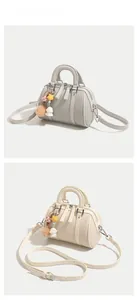 Detail of Boston bag with woven texture, leather trim and decorative bag charms