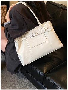Macro shot of cream-colored leather tote bag with metal buckle and textured finish