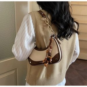 Gros plan d'un sac hobo bicolore avec glands en perles de bois porté à l'épaule