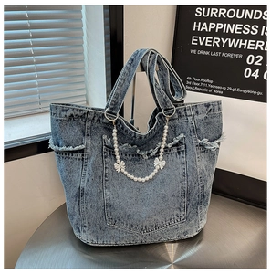 Detail view of denim tote bag with frayed edges and pearl chain with white bows