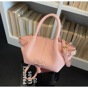 Detail der hellrosa Handtasche mit Litschi-Lederstruktur und goldenen Metallschnallen