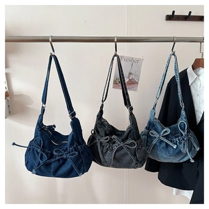 Detail of denim bow hobo bag showing the drawstring texture and washed fabric design