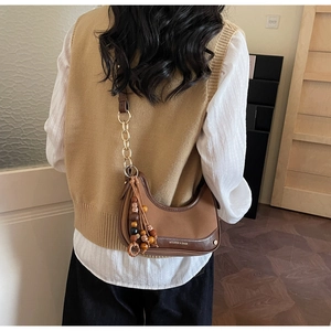 Gros plan du sac hobo marron avec bandoulière en chaîne et pompon en perles de bois