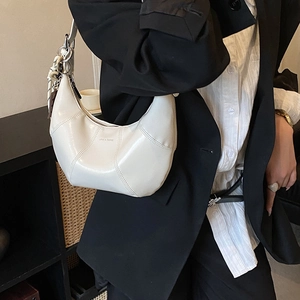 Detail of white glossy leather underarm bag with chain strap and silk scarf charm decor
