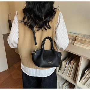 Detail einer schwarzen Handtasche aus Leder mit goldenem Logo in gemütlichem Ambiente