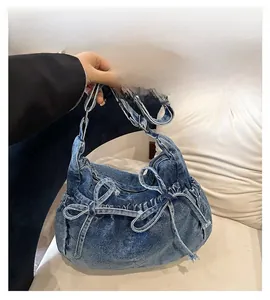 Detailed close-up of dark denim shoulder bag featuring stylish double bow drawstring knots