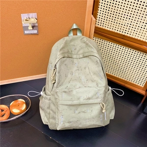 Detailed view of grey-green tie-dye backpack with white lightning embroidery and woven zipper pull