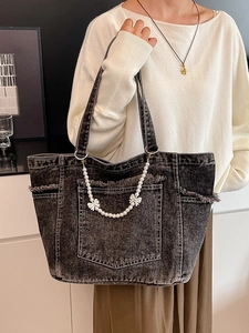 Large dark grey washed denim tote bag with pearl chain and bow details on a model
