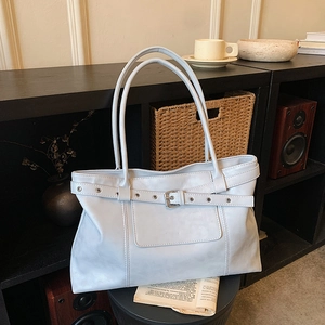 Light blue minimalist tote bag with silver buckle and leather straps on black chair
