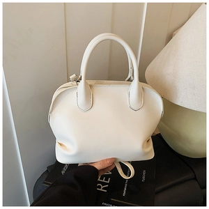 Detail view of cream leather shell bag with neat stitching and smooth handles