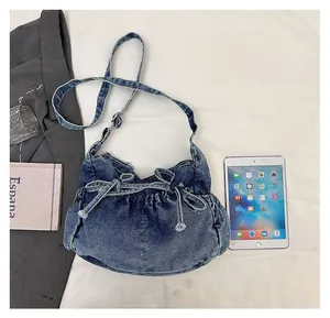 Blue denim bow shoulder bag shown next to a tablet for clear size comparison