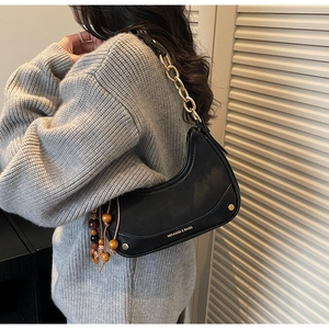 Detail of black half-moon bag featuring gold chain and decorative wooden beads