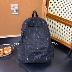 Detail view of black backpack side pocket with lightning print and adjustable white cords
