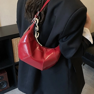 Detail of red patent leather hobo bag with black and white chain and Love & Peace text