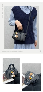 Detailed view of grey textured Boston bag with cute doll pendants and black handles