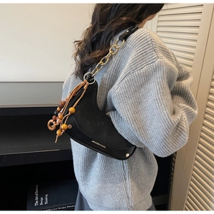 Détail d'un sac besace noir avec des perles en bois colorées et une chaîne dorée