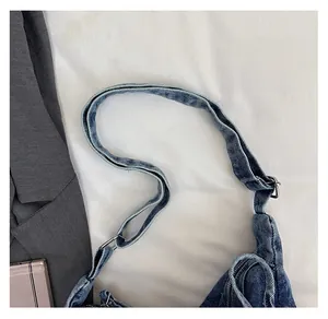 Detail of adjustable denim shoulder strap with silver metal buckle and reinforced stitching