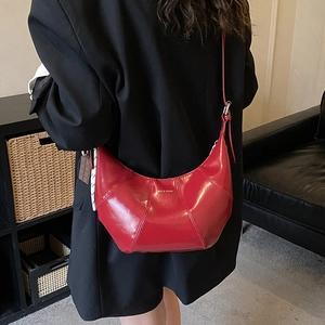 Detail of red crescent shoulder bag with glossy patent leather and golden logo