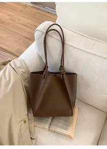 Detail of dark brown tote bag featuring knotted handles and lychee grain leather texture