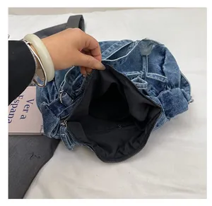 Detail view of the interior compartment and zipper pocket of the denim bow shoulder bag
