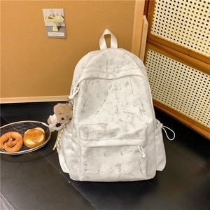Detail of white marble backpack with lightning embroidery and brown bear plush charm