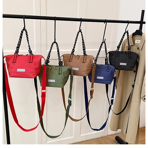 Detail of five plaid tote bags in various colors hanging on a minimalist rack