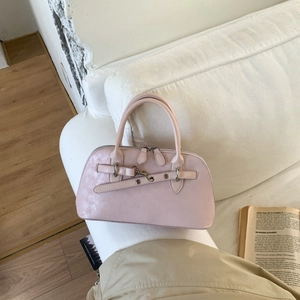 Close-up of pink frosted vintage leather handbag on a white sofa with decorative buckle
