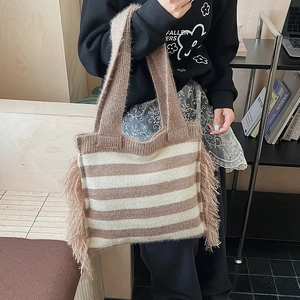 Detailed close-up of brown and beige striped knit tote bag with decorative side tassels