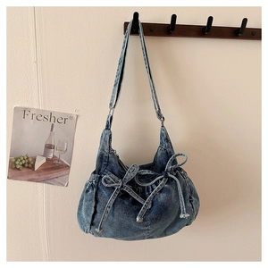 Detailed macro view of the bow decoration on a vintage blue denim crescent shoulder bag