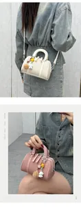Detail of Boston bag with woven texture, leather handles, and decorative plush charms