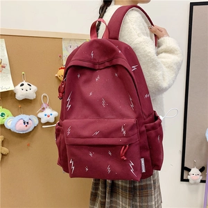 Detail view of burgundy canvas backpack featuring lightning pattern and side drawstring pocket