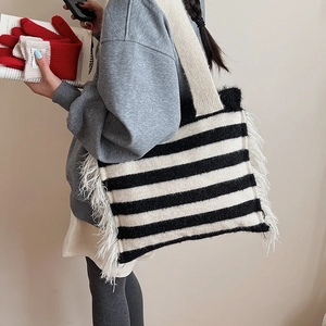 Detail showing the thick knitted texture and long white side tassels on the striped tote bag