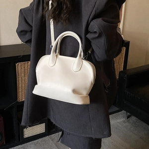 Chic off-white shell handbag styled with a grey blazer for a modern minimalist look