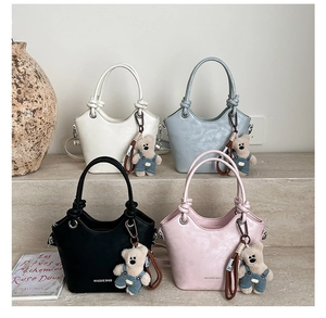 Detail of minimalist bucket bags in multiple colors featuring cute bear pendants