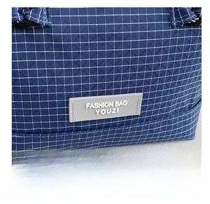 Detailed close-up of blue checkered fabric texture and fashion rubber tag on handbag