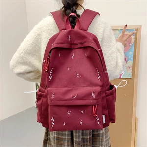 Detail view of burgundy canvas backpack with white lightning pattern and side label