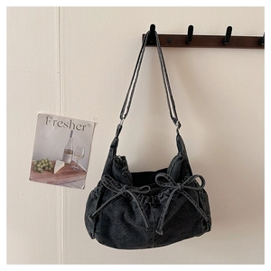 Detail shot of black denim crescent bag featuring stylish drawstring bow decorations