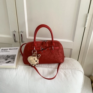 Close-up of red frosted leather Boston bag with silver buckles and cute teddy bear charm