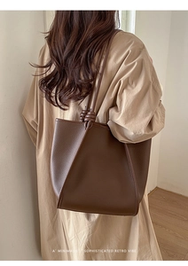 Detailed view of the dark brown lychee textured leather tote with unique double knot accents