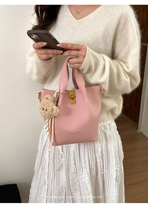 Detail of pink bucket bag with gold twist lock, leather texture and plush bear charm