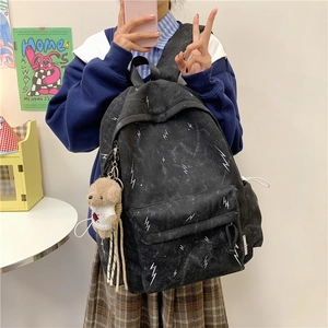 Detail of black canvas backpack featuring white lightning prints and cute bear pendant