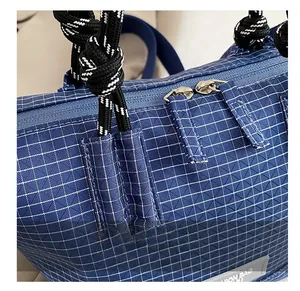 Detailed macro view of blue checkered nylon fabric with silver metal zipper and woven strap