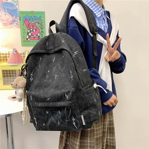 Detail of black backpack with white lightning print and cute plush bear charm accessory