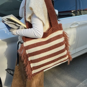 Close-up of a large striped knit tote bag with long side tassels in brown and beige colors