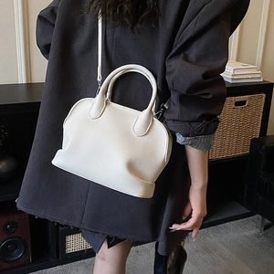 Detailed shot of white lychee grain leather shell bag worn with a charcoal coat
