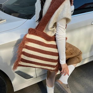 Detail of knitted tote bag with brown stripes and long fringe accents on the side