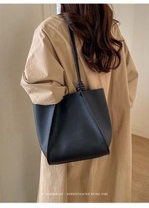 Detail of black pebbled leather tote bag with unique knotted strap and side fold design