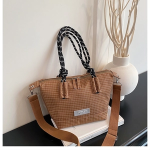 Detailed view of brown checkered tote bag featuring woven straps and stylish leather logo